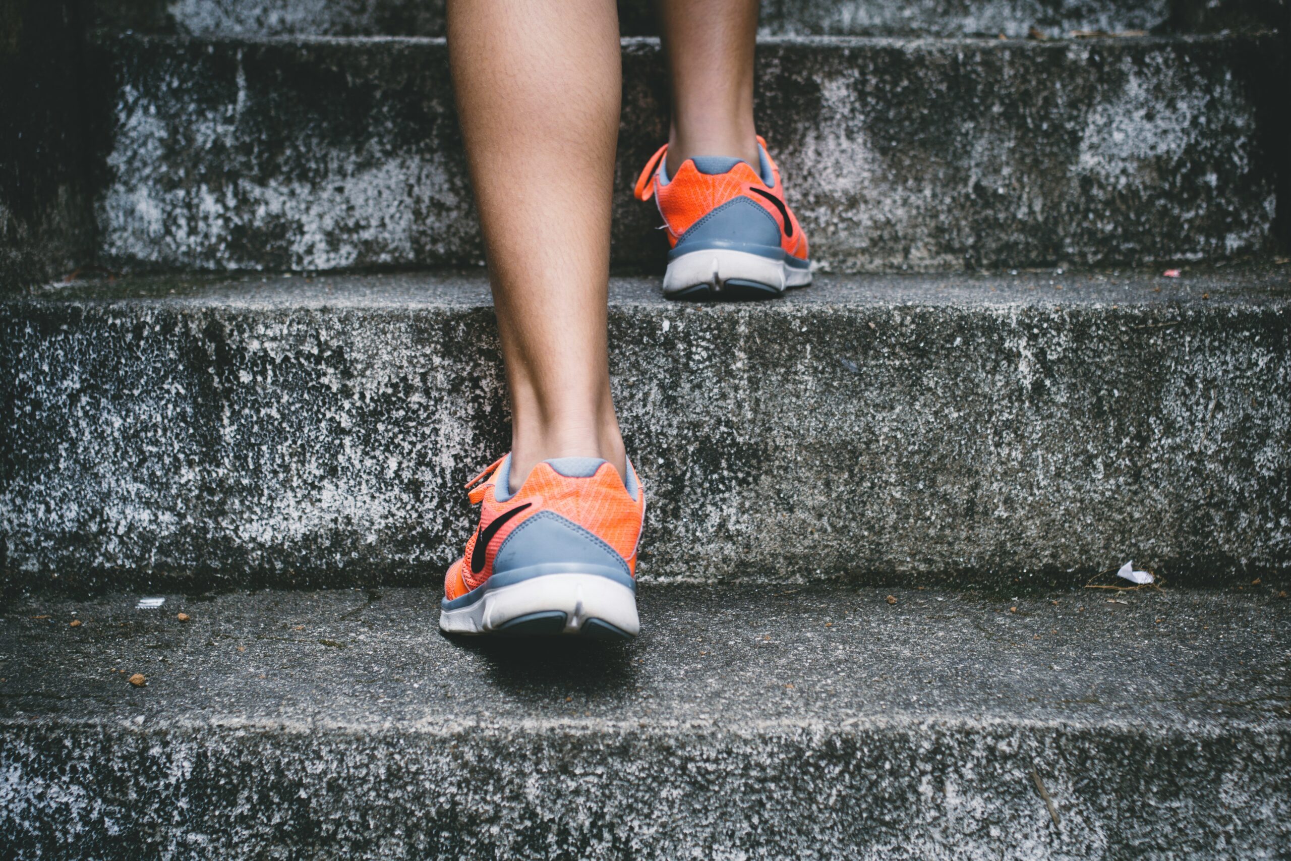 A close-up image of someone walking up steep stairs in trainers.